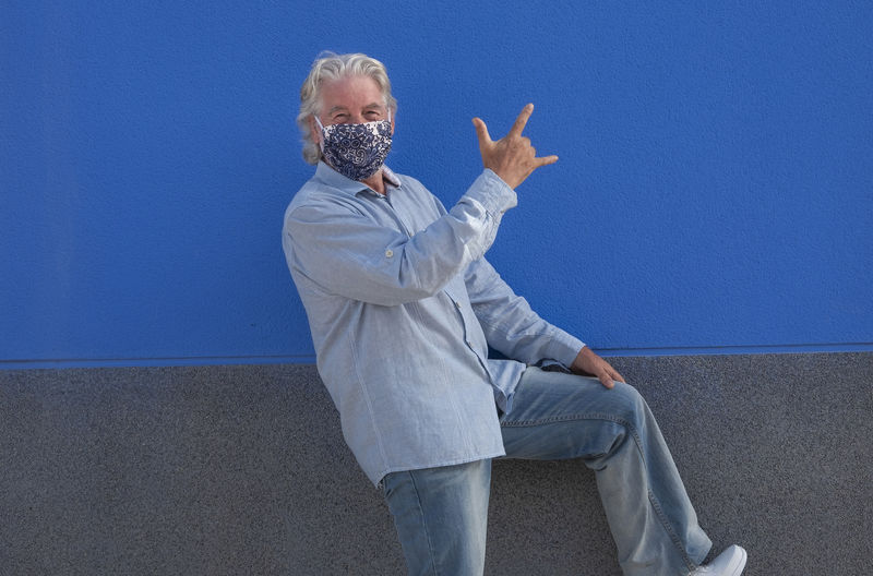Portrait of man gesturing against blue wall