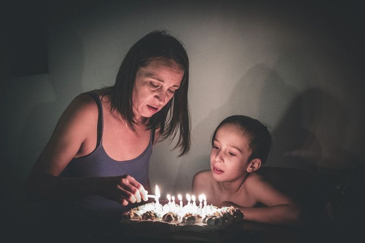 Mother burning birthday candles for son at home
