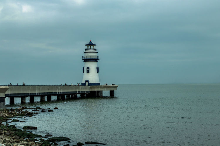 Lighthouse by sea against sky