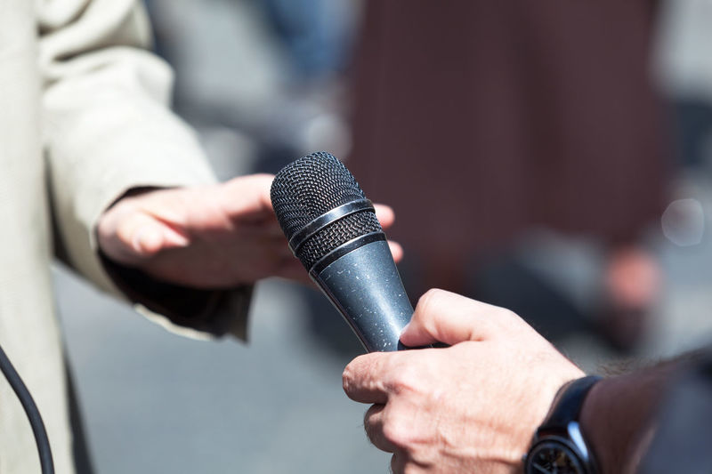Cropped hand of male journalist interviewing businessman