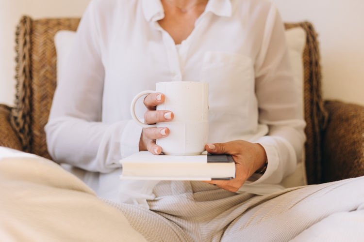 Midsection of woman using mobile phone while lying on bed at home