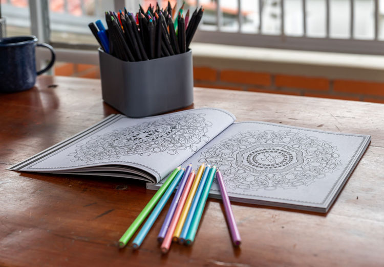 Mandala book for coloring with crayons in a desk in home office