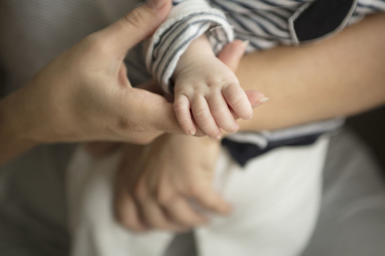 Cropped hands of mother holding newborn