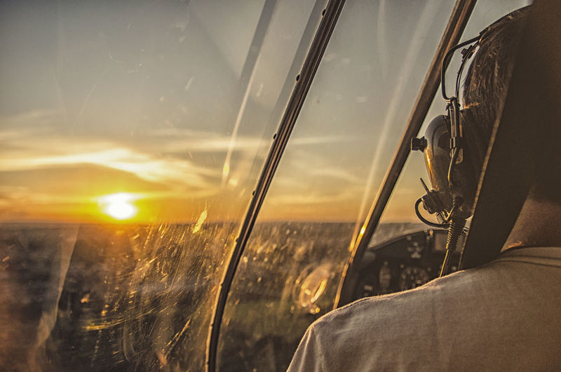 Rear view of pilot flying helicopter during sunset
