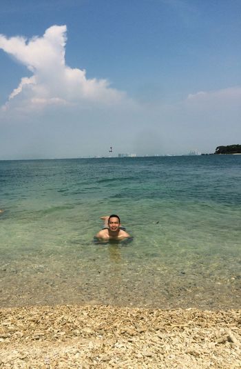 Young man swimming in sea against sky