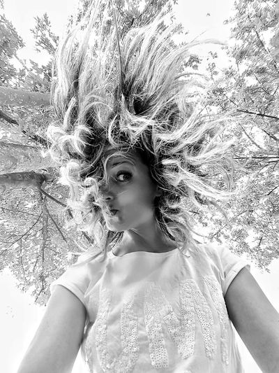 Portrait of beautiful young woman standing against tree