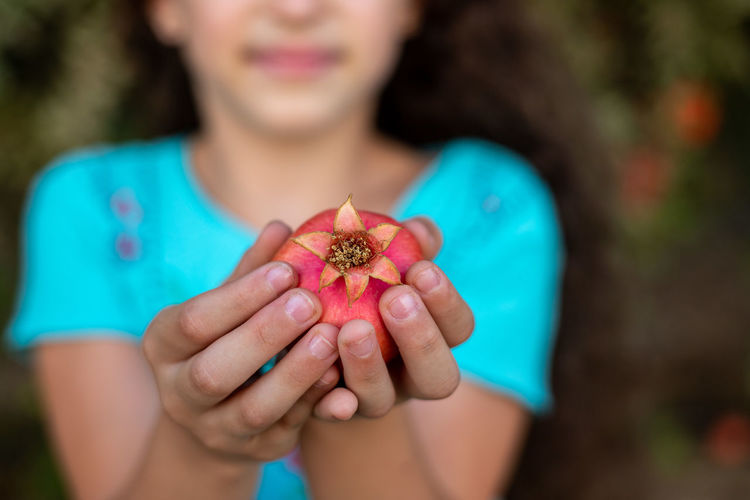 Midsection of woman holding pomegranate outdoors