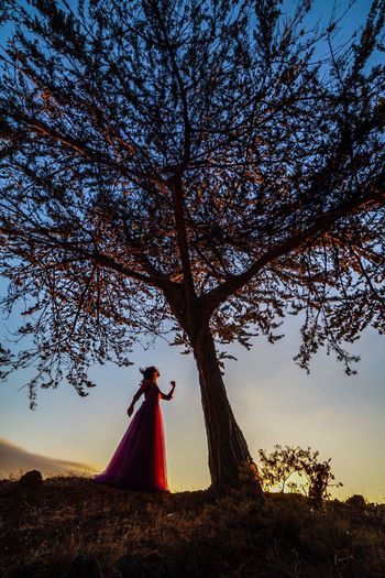 Woman standing by tree against sky