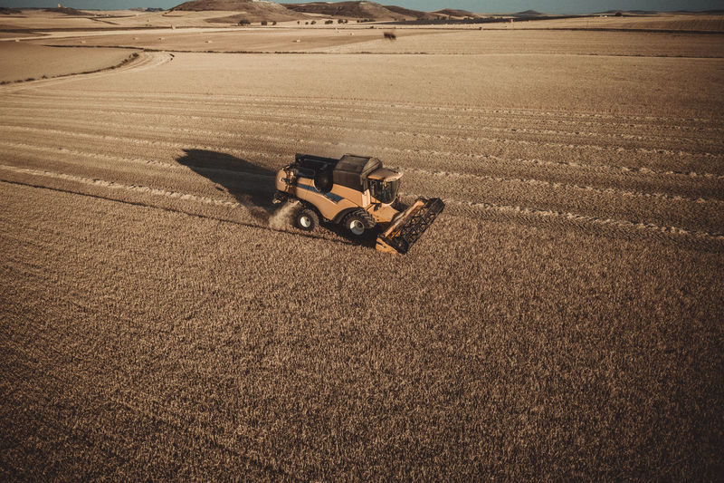 Combine harvester working at sunset from aerial view.