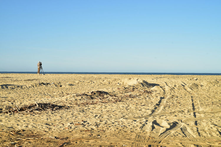 Young man photographer with camera on tripod on pacific ocean beach in baja california sur, mexico
