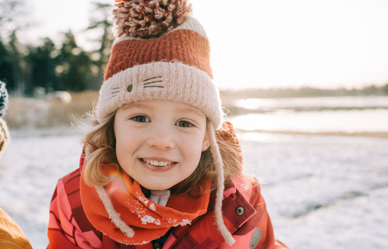 Close up portrait of a young girl sitting in the snow at sunset