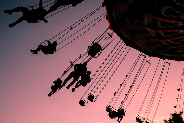 Low angle view of chain swing ride against sky during sunset