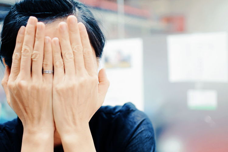 Close-up of shy woman covering face at home