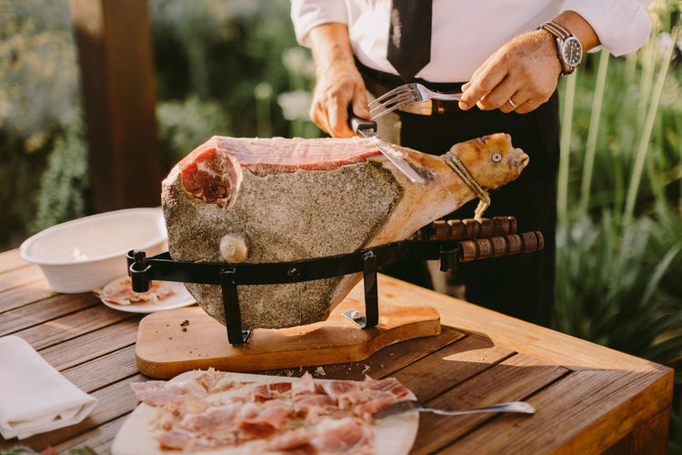 Midsection of man slicing meat outdoors