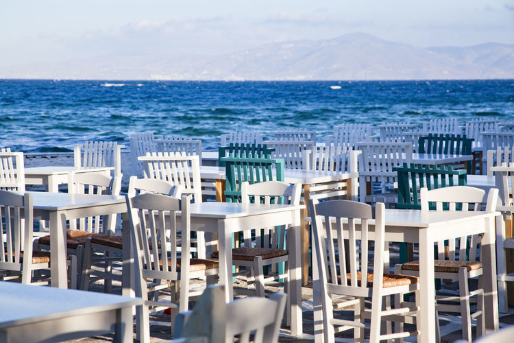 Chairs and tables at beach against sky