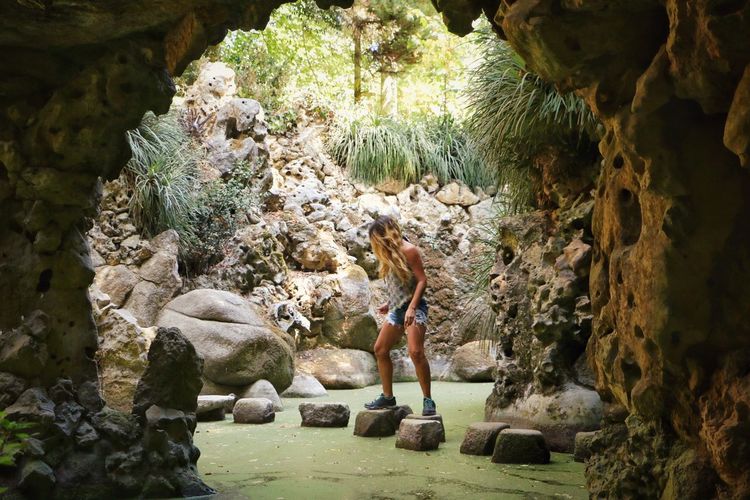 Full length of woman standing on stepping stone in cave
