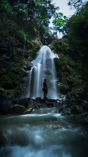 Man looking at waterfall in forest