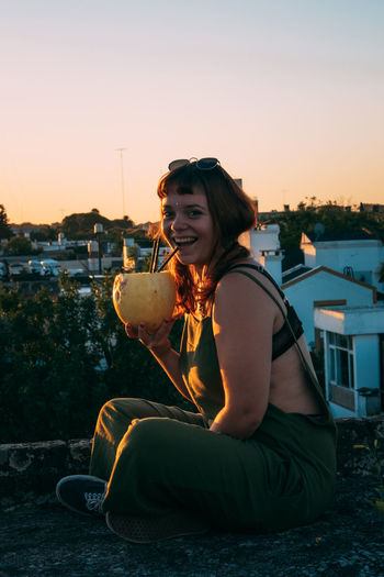 Portrait of young woman drinking with a melon on rooftop