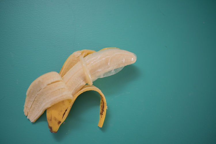 Directly above shot of banana wearing condom over blue background