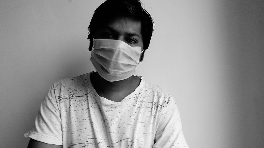 Portrait of young man against white background, mask