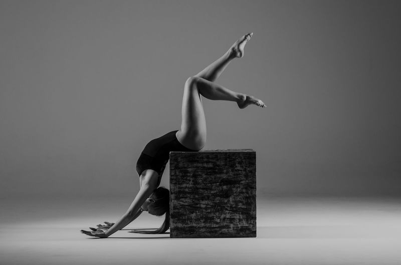 Full length of woman exercising against gray background