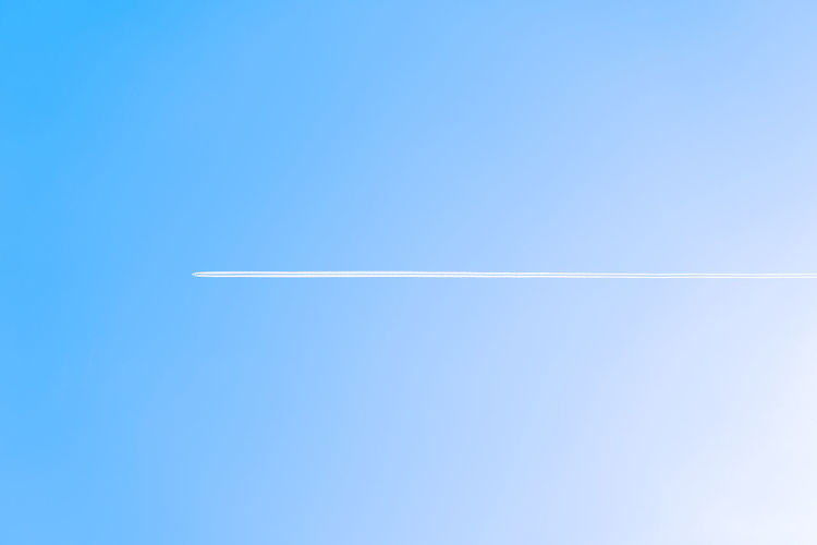 Low angle view of vapor trail / chemtrails against clear blue sky