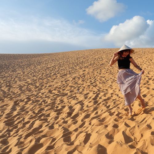 Young woman walking at desert against sky