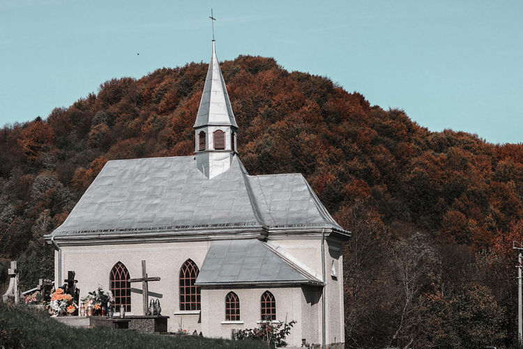 Church amidst trees and buildings against sky during autumn