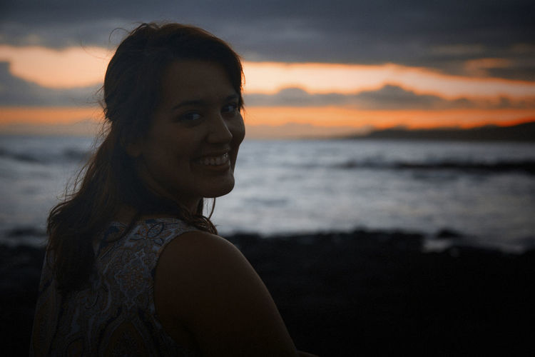 Portrait of smiling young woman at beach during sunset