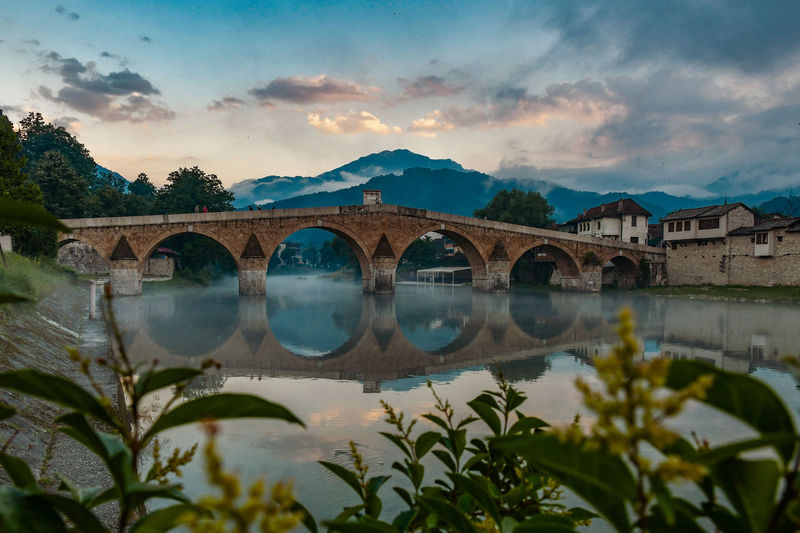 Arch bridge over river against sky