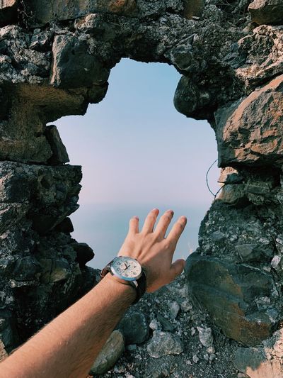 Cropped hand of person by hole in stone wall