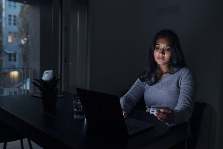 Woman holding credit card doing online shopping through laptop at home