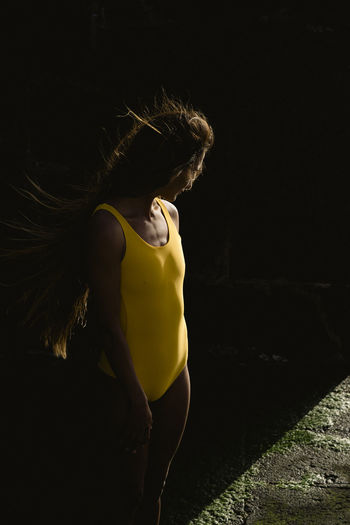 Full length of latin woman in yellow swimsuit against black background