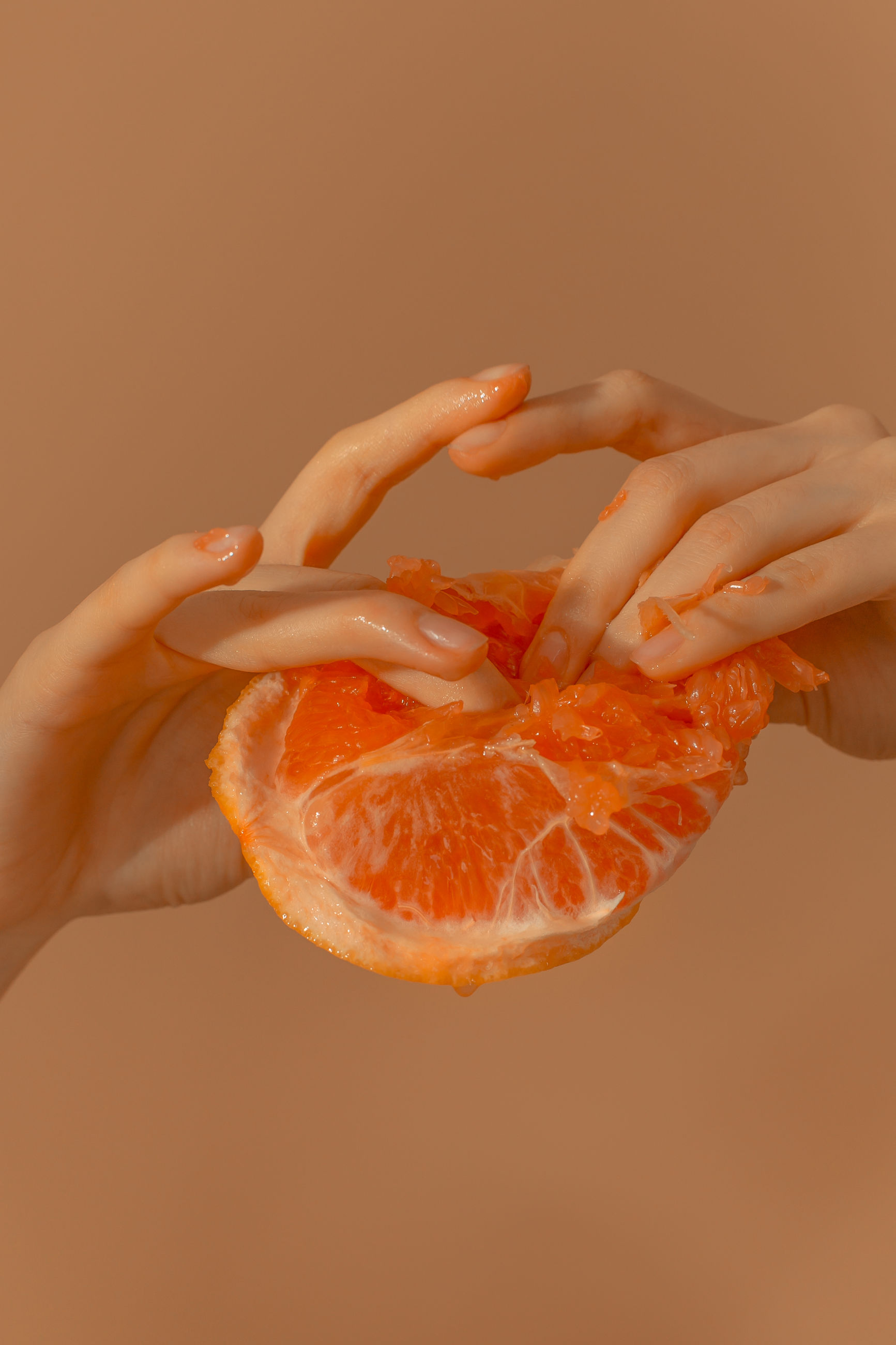 orange color, food, human hand, food and drink, human body part, indoors, holding, freshness, hand, healthy eating, fruit, one person, wellbeing, studio shot, citrus fruit, close-up, orange, body part, orange - fruit, finger, orange background
