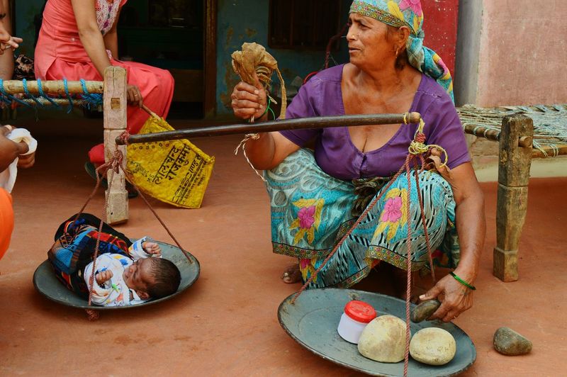 Senior woman measuring baby girl on weight scale