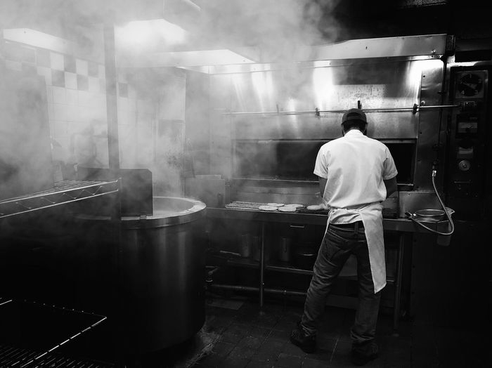 Full length rear view of chef working in commercial kitchen