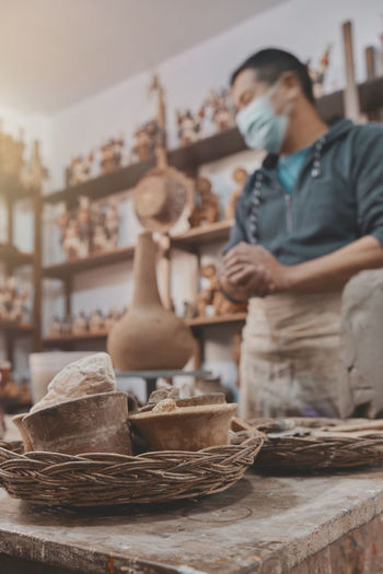 Man molding clay to make ceramics with his hands, artisan working in his workshop, selective focus