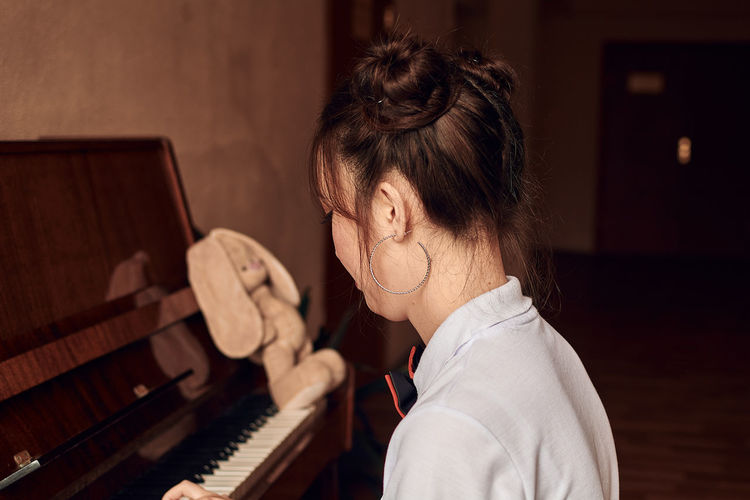 Asian high school student sitting at the piano