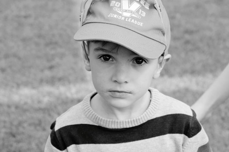 Portrait of boy wearing cap while standing on field