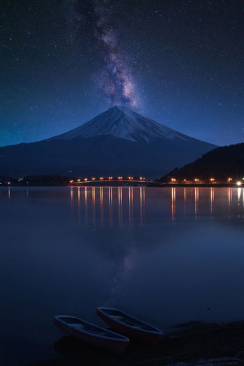 Scenic view of lake by mountains against sky at night