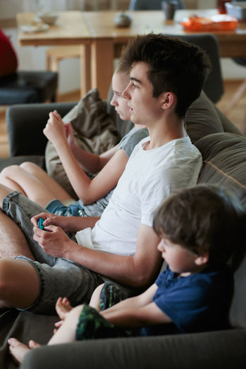 Siblings playing video game on couch at home
