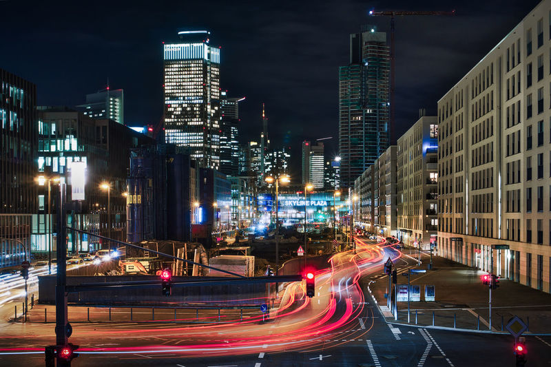 Light trails on city street amidst buildings at night
