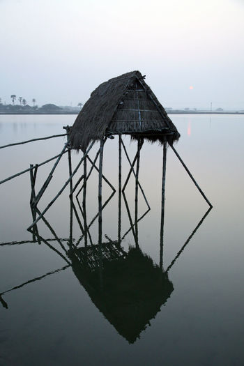 Damaged structure in lake against sky