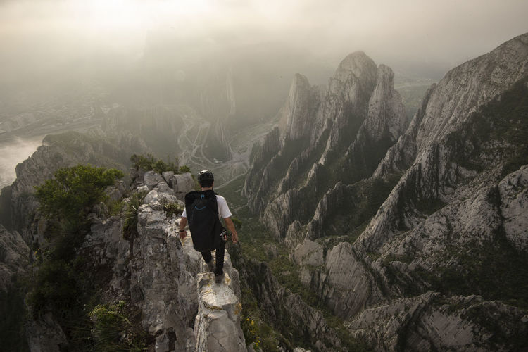 Rear view of man walking on rock in mountains