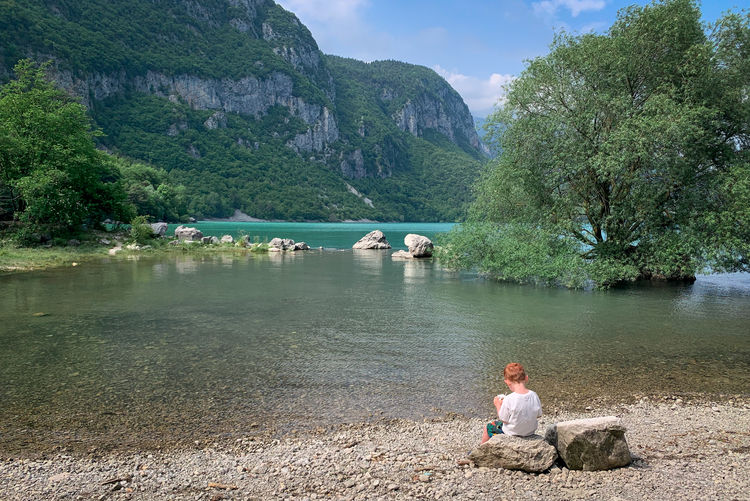 Man sitting on rock by lake