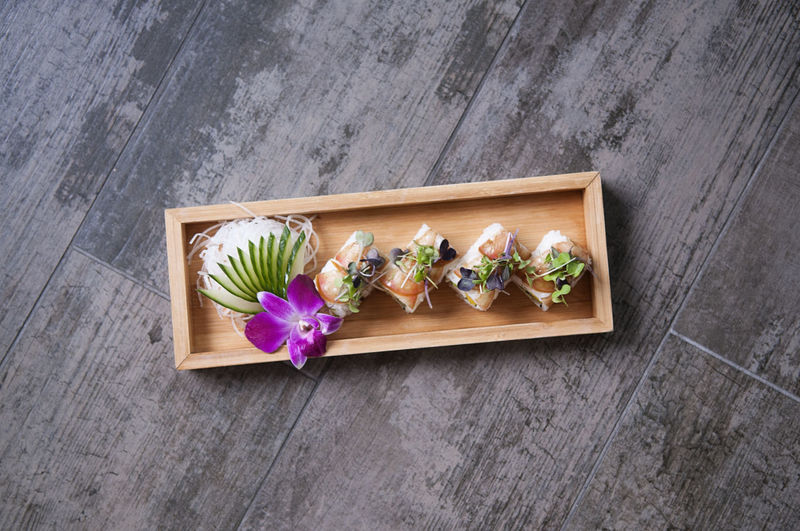 Sushi roll on a wooden tray toped with micro greens