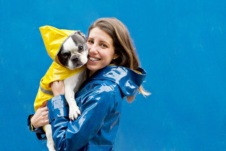 Low angle view of woman with dog against blue background