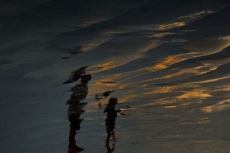 Reflection of silhouette man in lake against sky during sunset