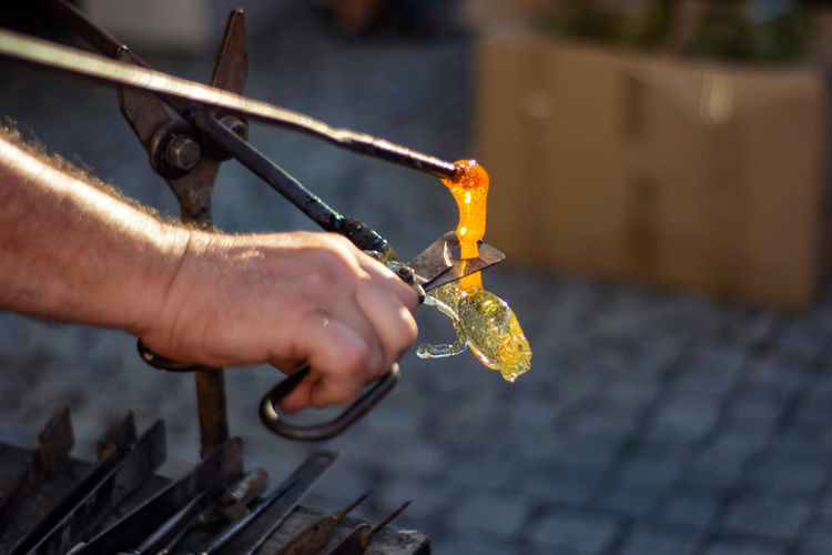 Cropped hand of man cutting glass on metal