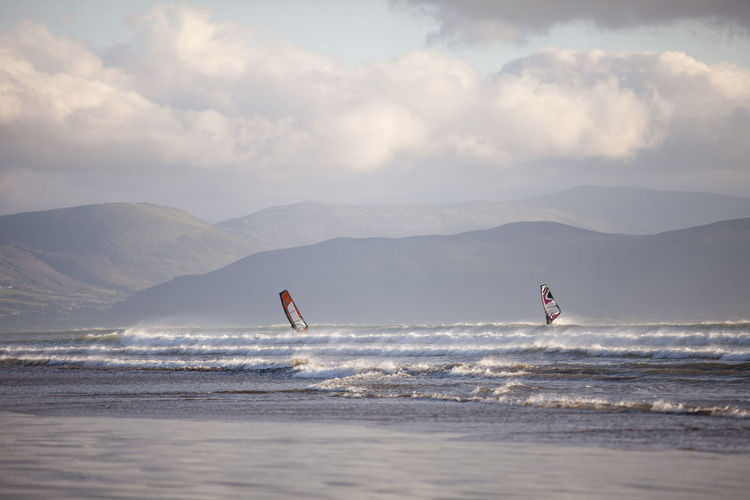 Windsurfing on beach against sky